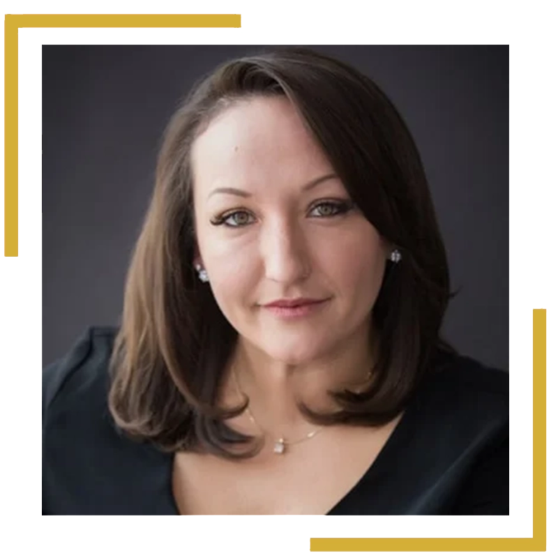 Woman with shoulder-length brown hair and a black top, looking at the camera against a dark background.